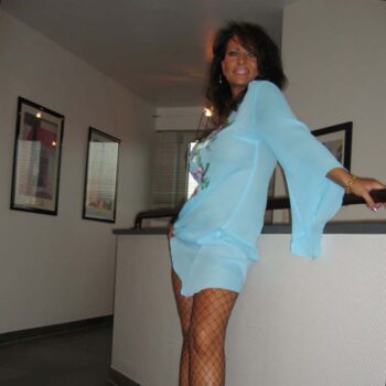 Femme dominatrice Paris élégante en robe bleue et bas résille plan Q mature