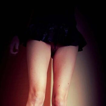 Femme dominatrice en lingerie noire, regard dur et posture autoritaire.